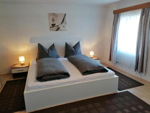 a white bed with blue pillows in a bedroom at Ferienwohnungen Kail Thomas in Obsteig