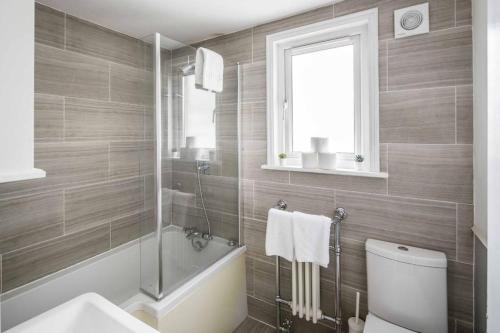 a bathroom with a tub and a toilet and a sink at Spacious 4 bed house in Croydon w/ parking for x2 cars! - Photo ID required in South Norwood