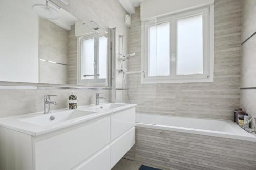 a white bathroom with a sink and a tub at Le Saint-Cloud Chic in Saint-Cloud