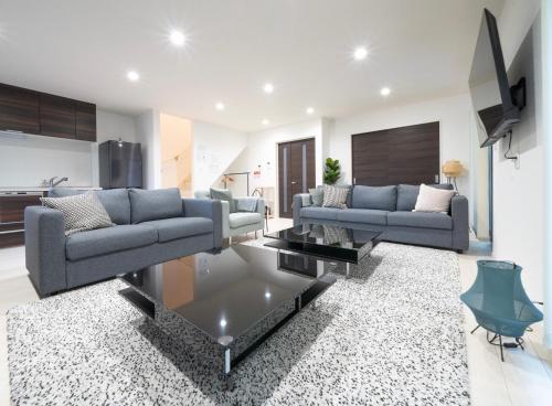 a living room with two couches and a tv at Rei Garden Resort in Kanayama