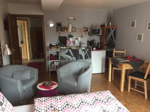 a living room with two chairs and a kitchen at Appartement Im alten Pfarrhaus in Bad Zwesten