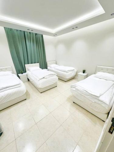 Habitación con 3 camas y cortina verde en شقة جميلة بغرفتين نوم ودخول ذاتي ١١, en Riad