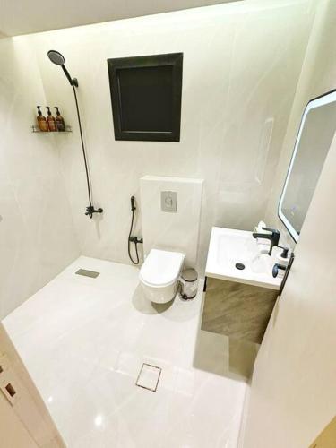 Baño blanco con aseo y lavamanos en شقة جميلة بغرفتين نوم ودخول ذاتي ١١, en Riad