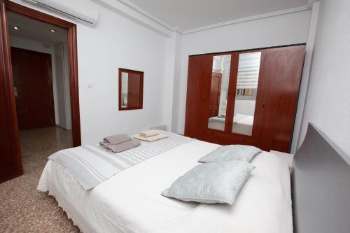 ein weißes Schlafzimmer mit einem großen weißen Bett mit Kissen in der Unterkunft Acogedor apartamento valencia 3 dormitorios in Aldaia