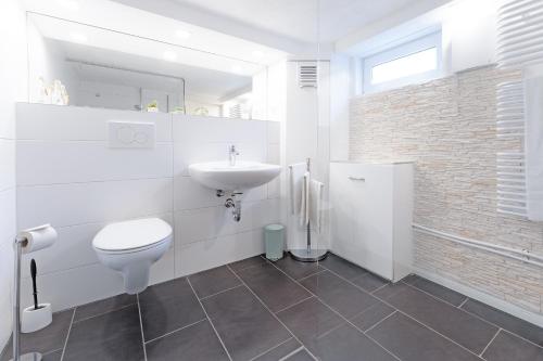 a white bathroom with a sink and a toilet at Fischerhus in Timmendorfer Strand