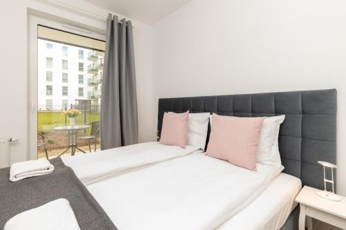 a bedroom with a large bed with pink pillows at TOTU HOME Marina Gdańsk Modern Apartment in Gdańsk