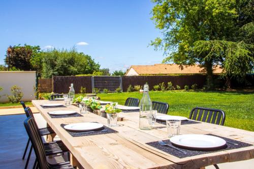 - une table en bois avec des assiettes et des bouteilles de vin dans l'établissement Les Olympiades - Magnifique Villa d'évasion, à Vendeuvre-du-Poitou