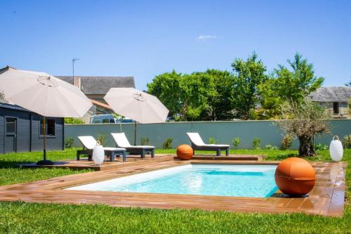a backyard with a swimming pool with chairs and umbrellas at Les Olympiades - Magnifique Villa d'évasion in Vendeuvre-du-Poitou
