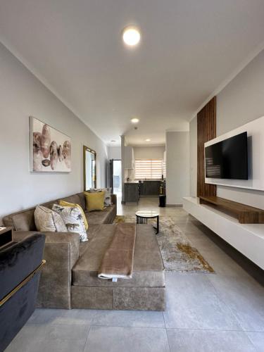 a living room with a couch and a flat screen tv at d’Pinx Nest in Gaborone