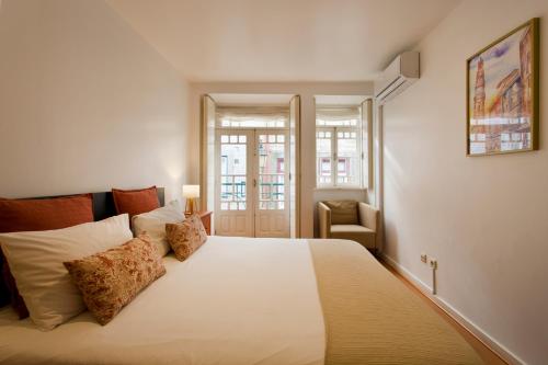 a bedroom with a large white bed and a chair at Home @ Porto Clérigos Apartment in Porto