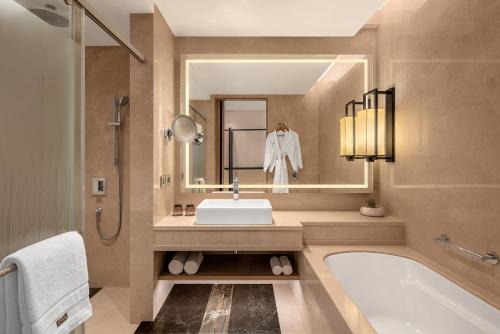 a bathroom with a sink and a tub and a mirror at The Westin Goa in Vagator
