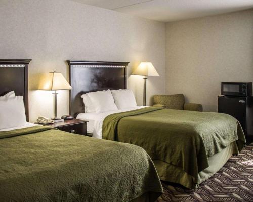 a hotel room with two beds and a chair at Quality Inn & Suites Mansfield in Mansfield