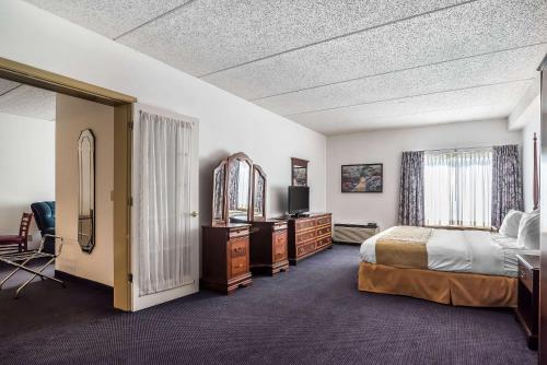 ラッサムにあるQuality Inn & Suites Albany Airportのベッド、デスク、テレビが備わるホテルルームです。