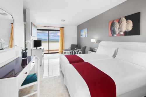 a hotel room with a white bed and a desk at Elba Lucía Sport & Suite Hotel in Costa de Antigua