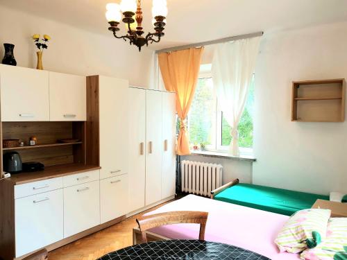 kuchnia z białymi szafkami, stołem i oknem w obiekcie Rooms by Kino Femina w Warszawie