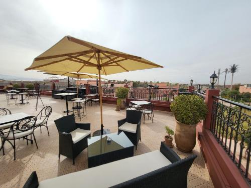un patio con tavoli, sedie e ombrellone di Riad Soir De Marrakech a Marrakech
