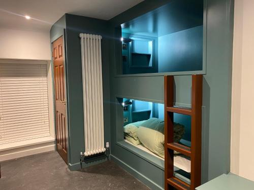a bedroom with a blue wall with a bunk bed at The Butchers Arms - Grill Pub and Accommodation in Merthyr Tydfil
