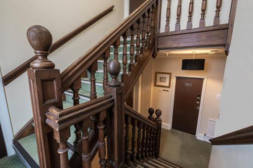 a winding staircase with wooden railings and a black door at Barrington Lodge in Crawley