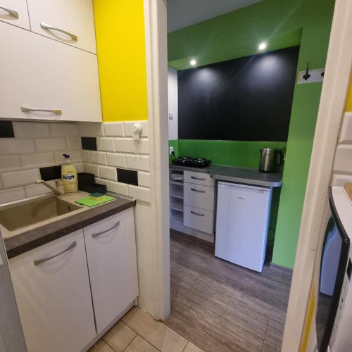 una piccola cucina con armadi bianchi e pareti verdi di Orange Apartment Kraków a Cracovia