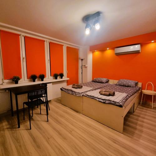 una camera da letto con pareti arancioni, un letto e una scrivania di Orange Apartment Kraków a Cracovia