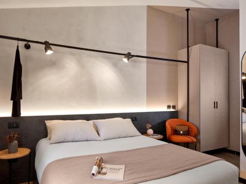 a bedroom with a large bed and a orange chair at Hotel Antica Fonte in Brescia