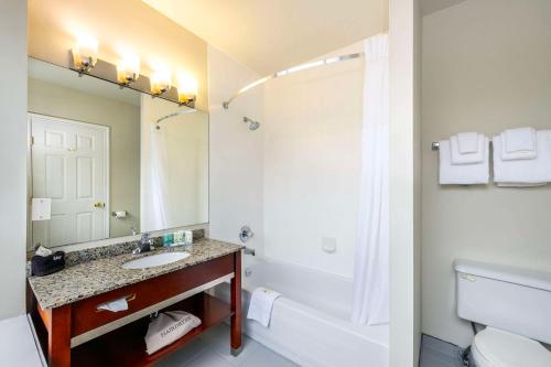 a bathroom with a sink and a tub and a toilet at Quality Inn & Suites in Vancouver