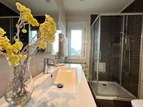 een badkamer met een wastafel en een vaas met gele bloemen bij CASA LUMERMA in Taboadela