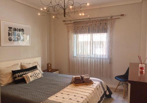 um quarto com uma cama com um lustre e uma janela em Estrela do Mar em Gafanha da Nazaré