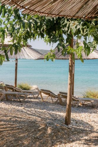 a group of chairs and umbrellas on a beach at PAVI APARTMENTS Life Style House with private pool in Kornić