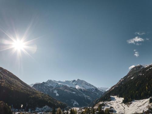 a sun shining over a snowy mountain valley at Urban Nature Bad Gastein - Badeschloss in Bad Gastein