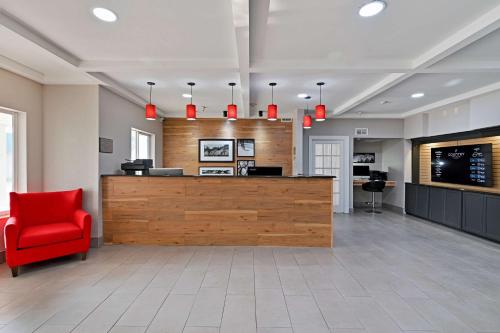 a waiting room with a red chair and a counter at Country Inn & Suites by Radisson, Bloomington-Normal Airport, IL in Bloomington
