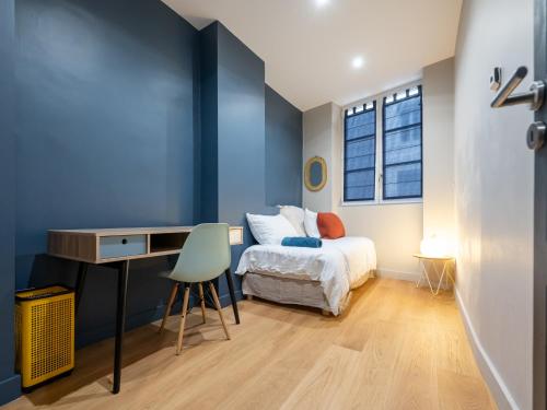 - une chambre avec des murs bleus, un lit et un bureau dans l'établissement L'Atelier,T3,au pied de l'Opéra, Climatisé, CHECK-IN AUTONOME 24H sur 24H, à Lyon