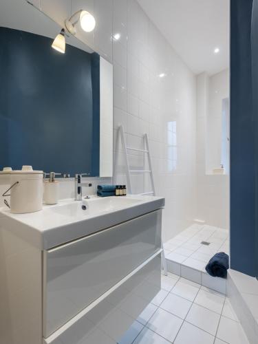 une salle de bain blanche avec un lavabo et un miroir dans l'établissement L'Atelier,T3,au pied de l'Opéra, Climatisé, CHECK-IN AUTONOME 24H sur 24H, à Lyon