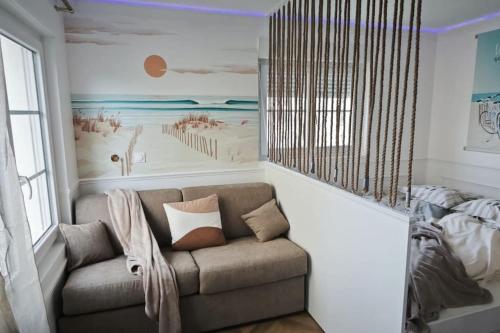 een woonkamer met een bank en een strandmuurschildering bij Perle Berckoise - studio - 250m de la plage - 1er étage in Berck-sur-Mer