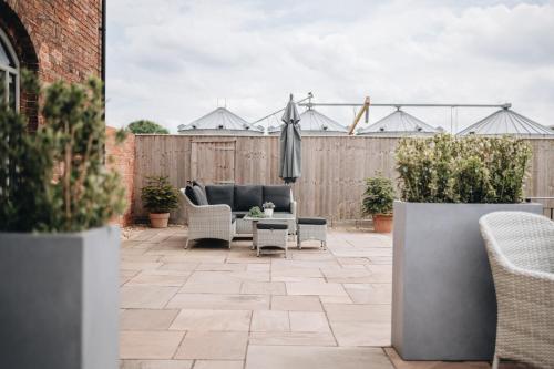 a patio with a couch and chairs and a fence at The Old Granary in Barnetby le Wold