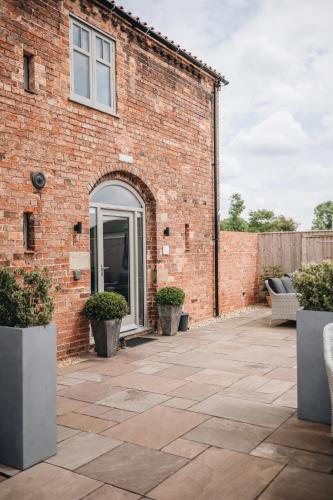 a brick building with a patio with potted plants at The Old Granary in Barnetby le Wold