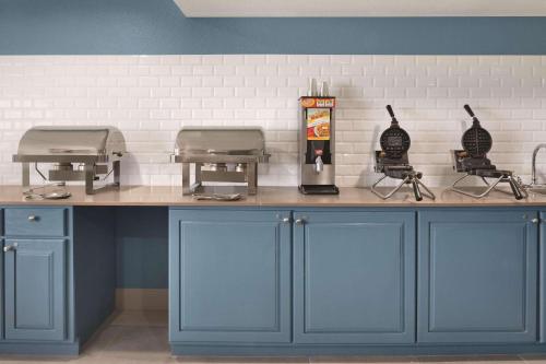 een keuken met blauwe kasten en een aanrecht met twee apparaten bij Country Inn & Suites by Radisson, Pella, IA in Pella