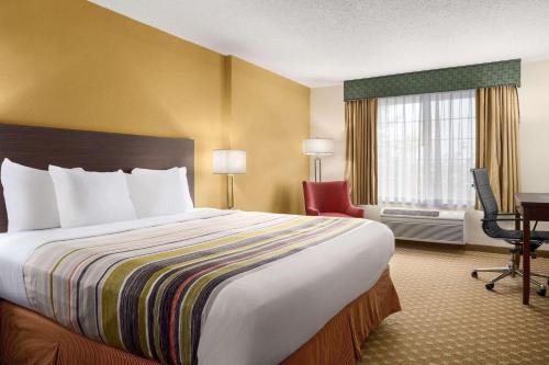 a hotel room with a large bed and a desk at Country Inn & Suites by Radisson, Manteno, IL in Manteno