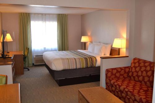 a hotel room with a bed and a couch at Country Inn & Suites by Radisson, Fairview Heights, IL in Fairview Heights