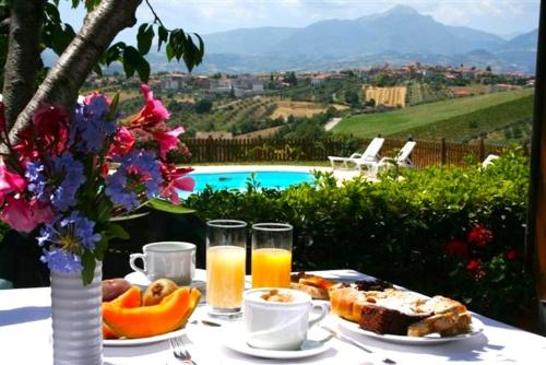 a table with breakfast food and a view of a pool at Agriturismo Villa Fiore in Torano Nuovo