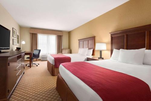 a hotel room with two beds and a flat screen tv at Country Inn & Suites by Radisson, Topeka West, KS in Topeka