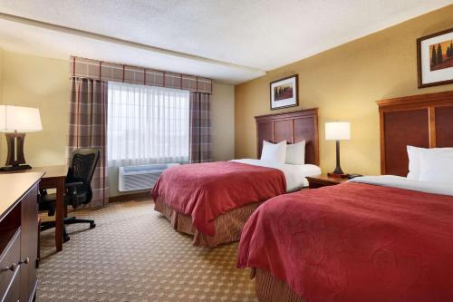 a hotel room with two beds and a desk at Country Inn & Suites by Radisson, Kalamazoo, MI in Kalamazoo