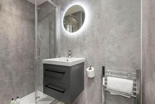 a bathroom with a sink and a shower with a mirror at The Golf Cottage - 30 Seconds to The Old Course in St Andrews