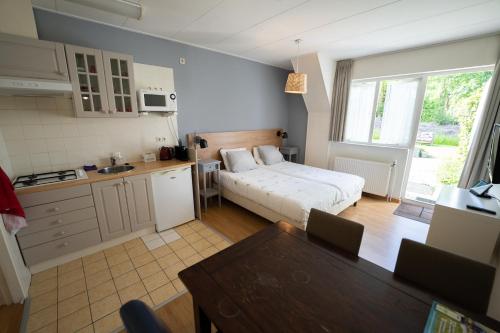 a bedroom with a bed and a kitchen with a table at Hofstede Villetta in Zonnemaire