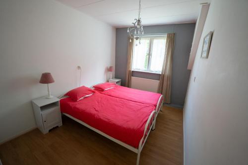 a bedroom with a red bed and a window at Hofstede Villetta in Zonnemaire