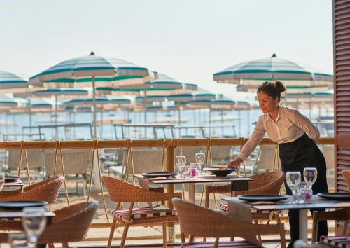 uma mulher de pé numa mesa num restaurante em GranSerena Hotel em Torre Canne