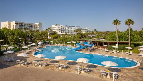 einen großen Pool mit Stühlen, Sonnenschirmen und einer Rutsche in der Unterkunft GranSerena Hotel in Torre Canne