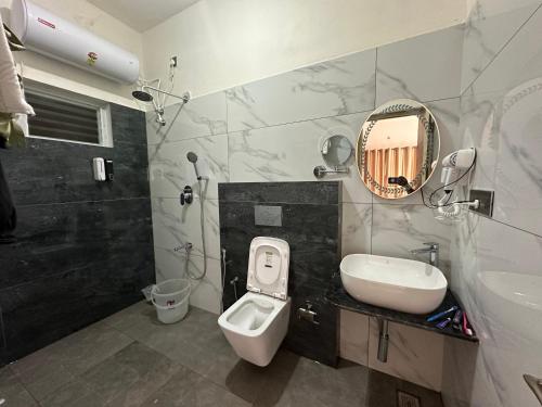 a bathroom with a sink and a toilet and a mirror at Coorg Jungle Mist in Madikeri