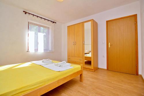 a bedroom with a yellow bed and a window at Apartment Dunato I in Šilo