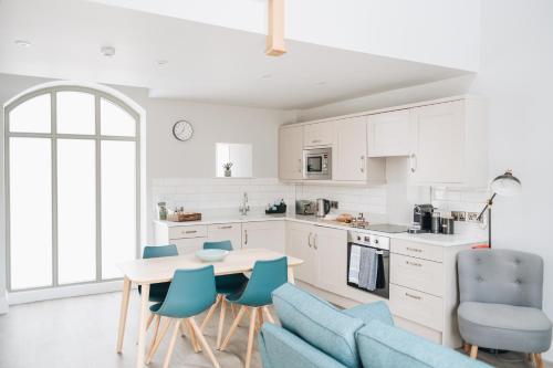 a kitchen with a table and blue chairs at The Old Granary in Barnetby le Wold